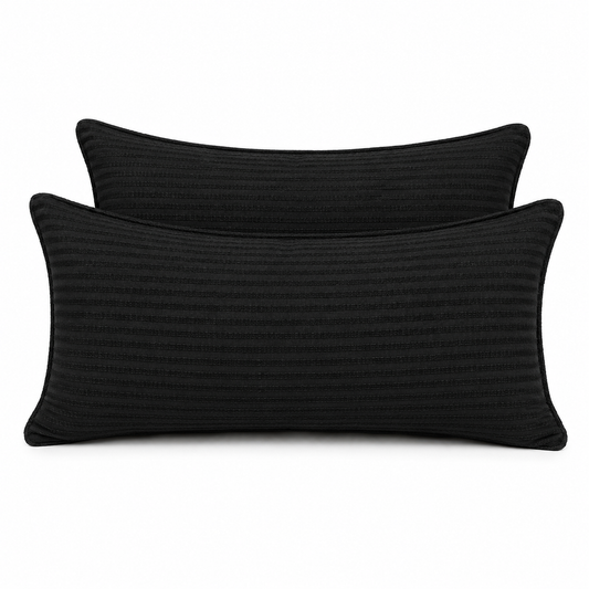 Coussins rectangulaires noirs unis tissés, posés sur un fauteuil dans une ambiance moderne et élégante