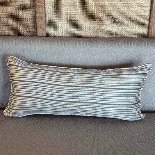 Coussin rectangulaire à rayures fines taupe et écru posé sur un canapé taupe dans une ambiance naturelle et élégante
