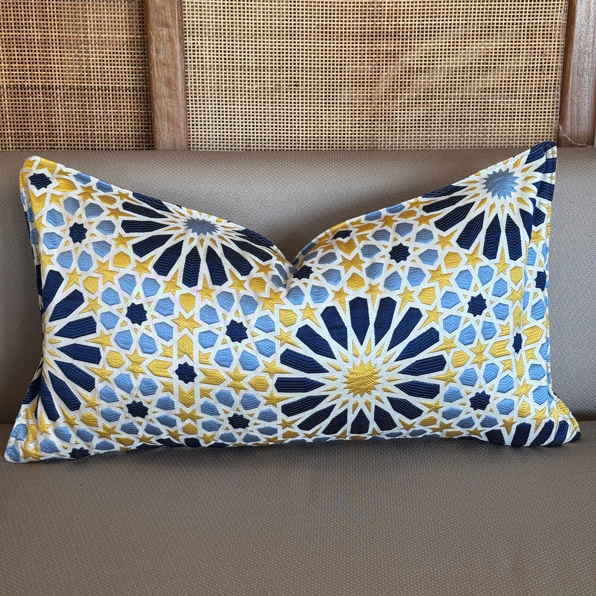 Coussin rectangulaire décoratif en tissu tissé marocain à motif zellij, teintes bleu et jaune, présenté sur canapé dans une ambiance élégante et contemporaine.