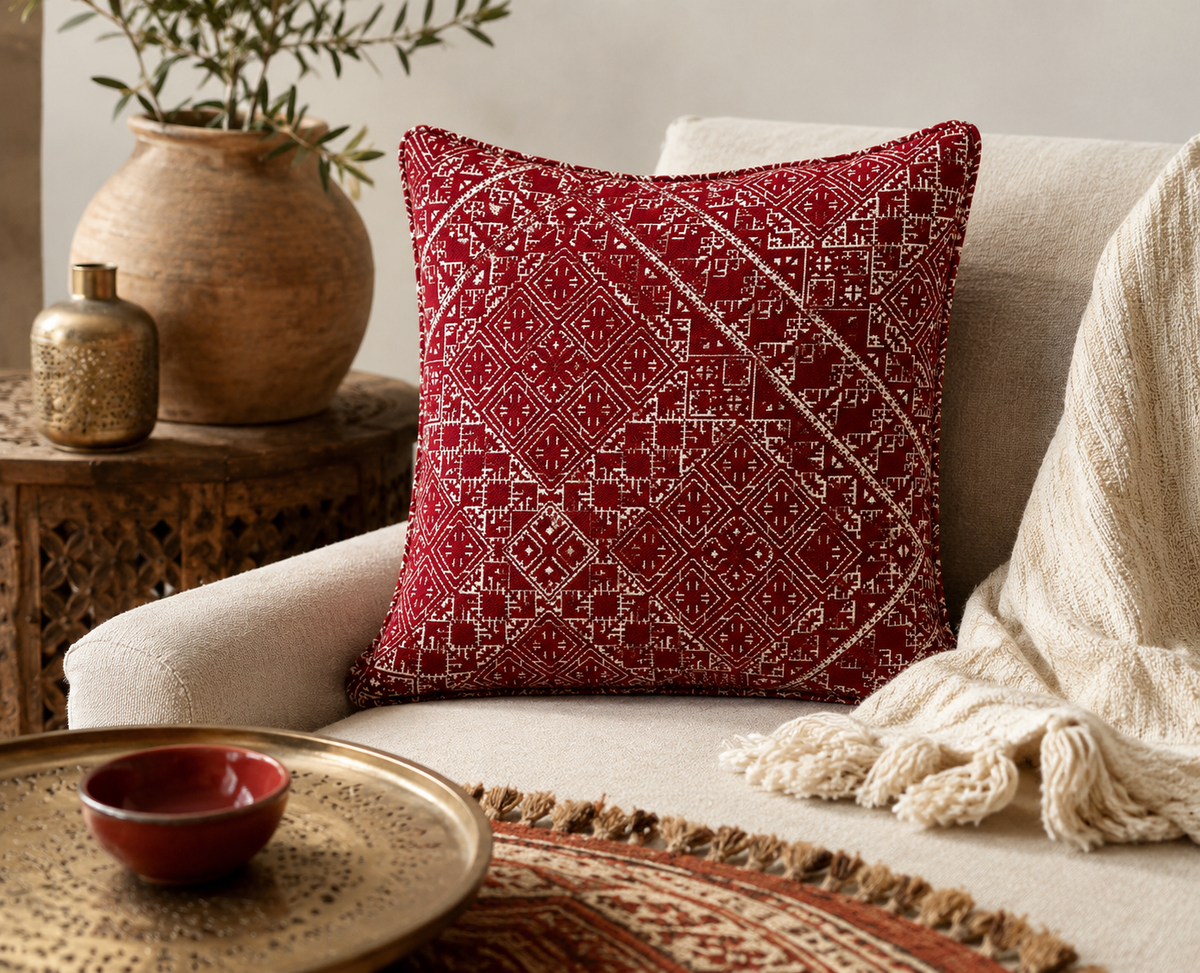 Coussin tarz rouge à motifs géométriques marocains dans une ambiance néobeldi chaleureuse avec décoration artisanale et canapé beige – Biyadi Collection.