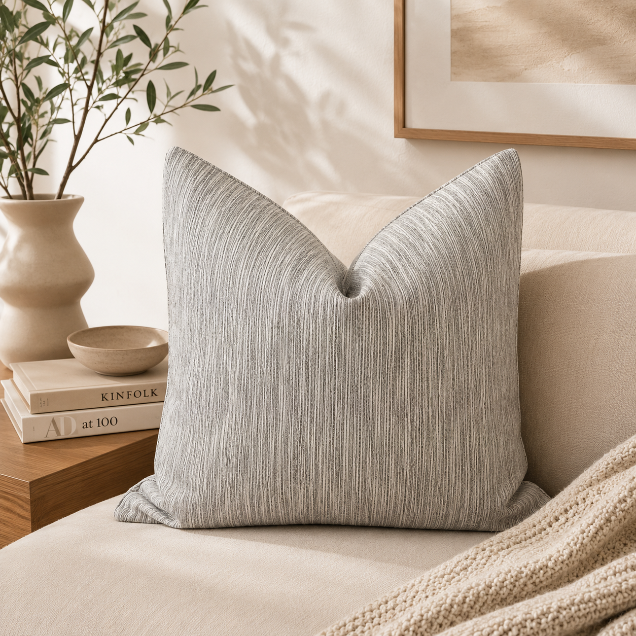 Coussin décoratif taupe texturé dans une ambiance minimaliste chic avec canapé beige, décoration naturelle et lumière douce.