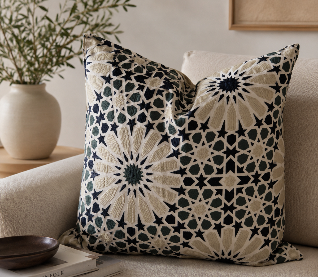 Coussin décoratif à motif zellige bleu, vert et écru posé sur un canapé beige dans une ambiance élégante et chaleureuse avec décoration naturelle et moderne.
