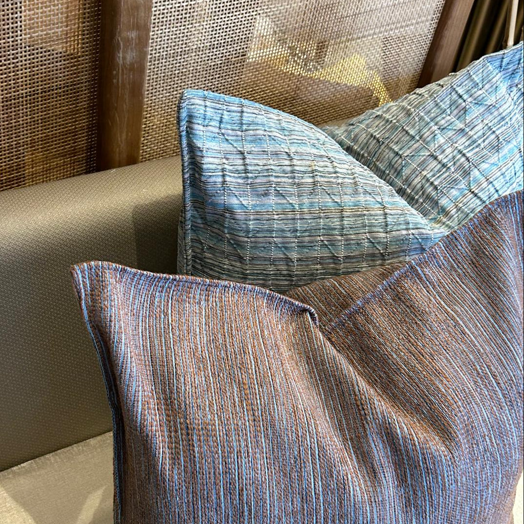 Coussins décoratifs en tissus marocains texturés aux fines rayures bleu et tons terre, association élégante et haut de gamme.