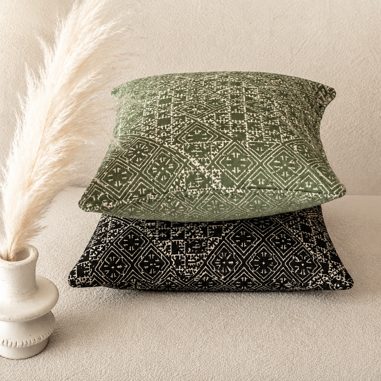 Deux coussins décoratifs en tissu Tarz Gharza tissé au Maroc, avec motif géométrique effet brodé en vert sauge et noir, présentés dans une ambiance élégante et contemporaine.