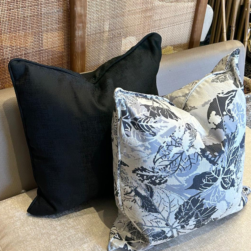 Duo de coussins décoratifs en tissu marocain : un coussin uni noir et un coussin à motif branchage noir et ivoire, finition élégante.