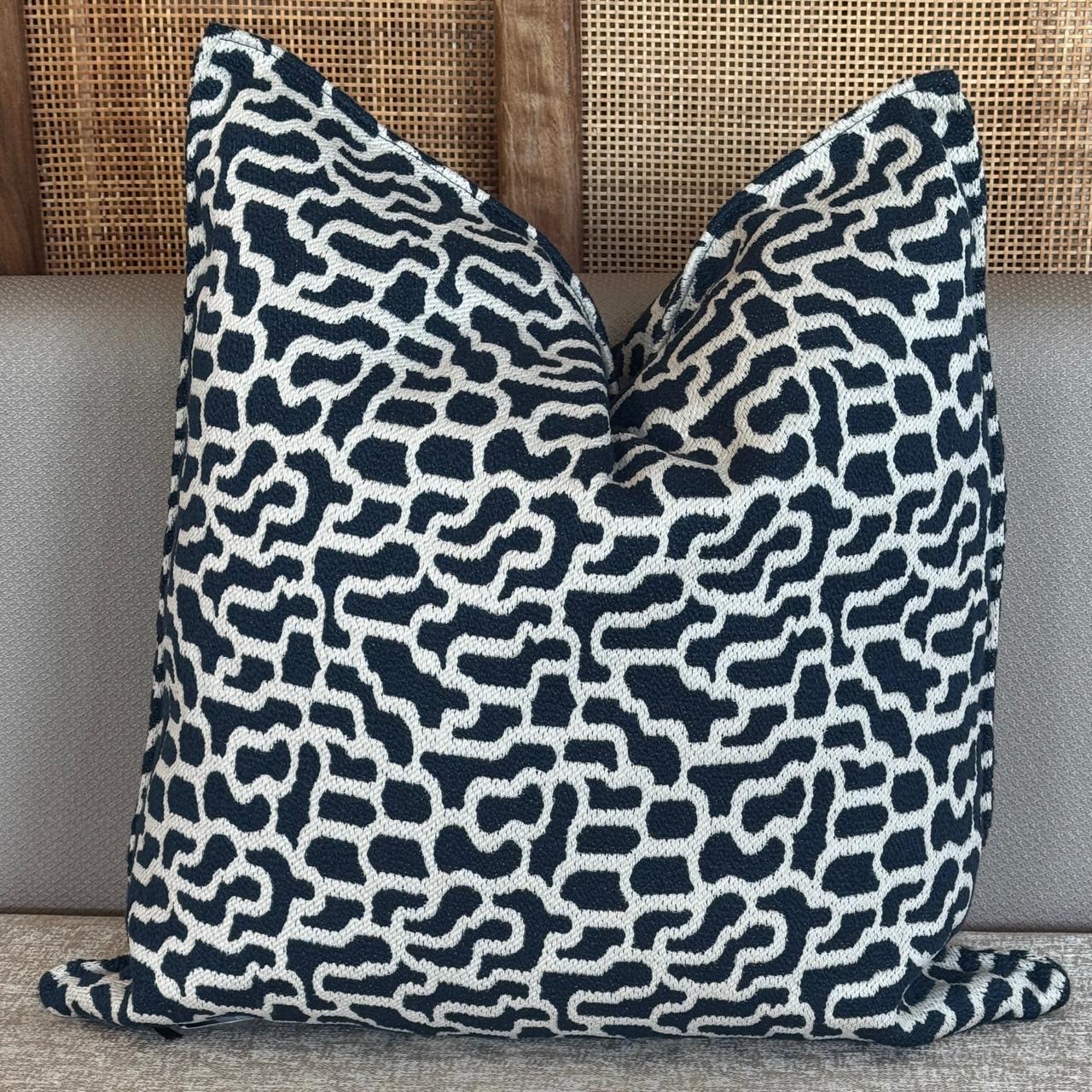 Coussin décoratif  bleu et ivoire avec motif abstrait en relief, au style moderne et graphique.