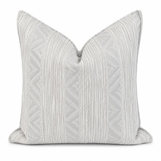 Coussin beige texturé à motifs géométriques grises dans une ambiance néobeldi élégante avec canapé clair et décoration minimaliste – Biyadi Collection.