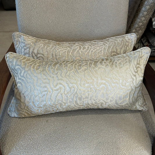 Coussin rectangulaire à motif organique beige lumineux en tissu texturé, posé sur fauteuil clair