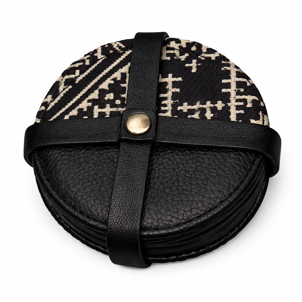 Pack de sous-tasses rondes noires en cuir et tissu Tarz à motifs écrus, maintenu par une attache en cuir.