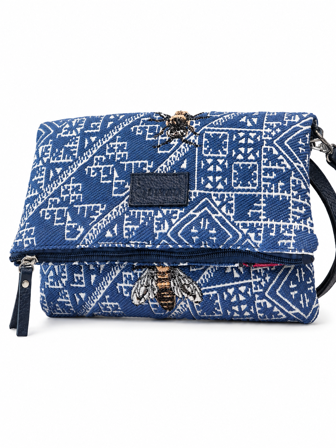 Sac bandoulière bleu jean en tissu marocain tissé avec motif géométrique et broderie abeille, fermeture zippée et finitions en cuir, création exclusive Biyadi Collection fabriquée au Maroc.