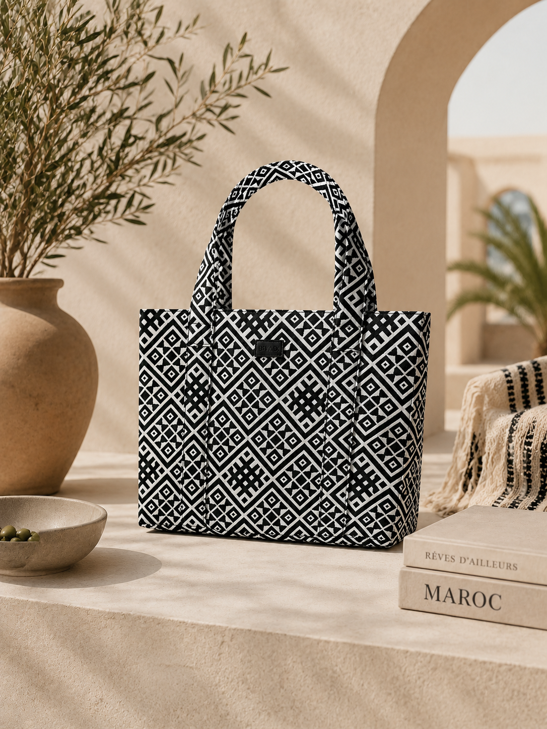 Sac cabas Biyadi Collection en tissu tissé noir et écru à motifs géométriques, présenté dans une ambiance élégante aux tons beige.