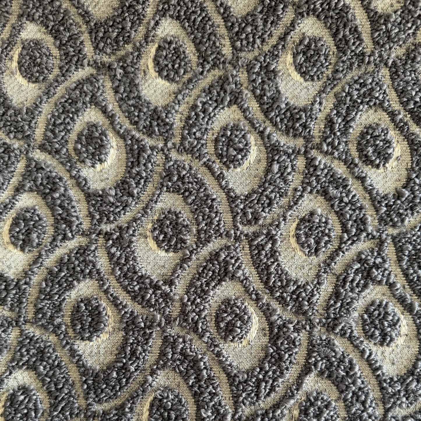 Gros plan sur un tissu bouclette gris  à motif géométrique en relief, tissé au Maroc pour l'ameublement et la décoration intérieure.