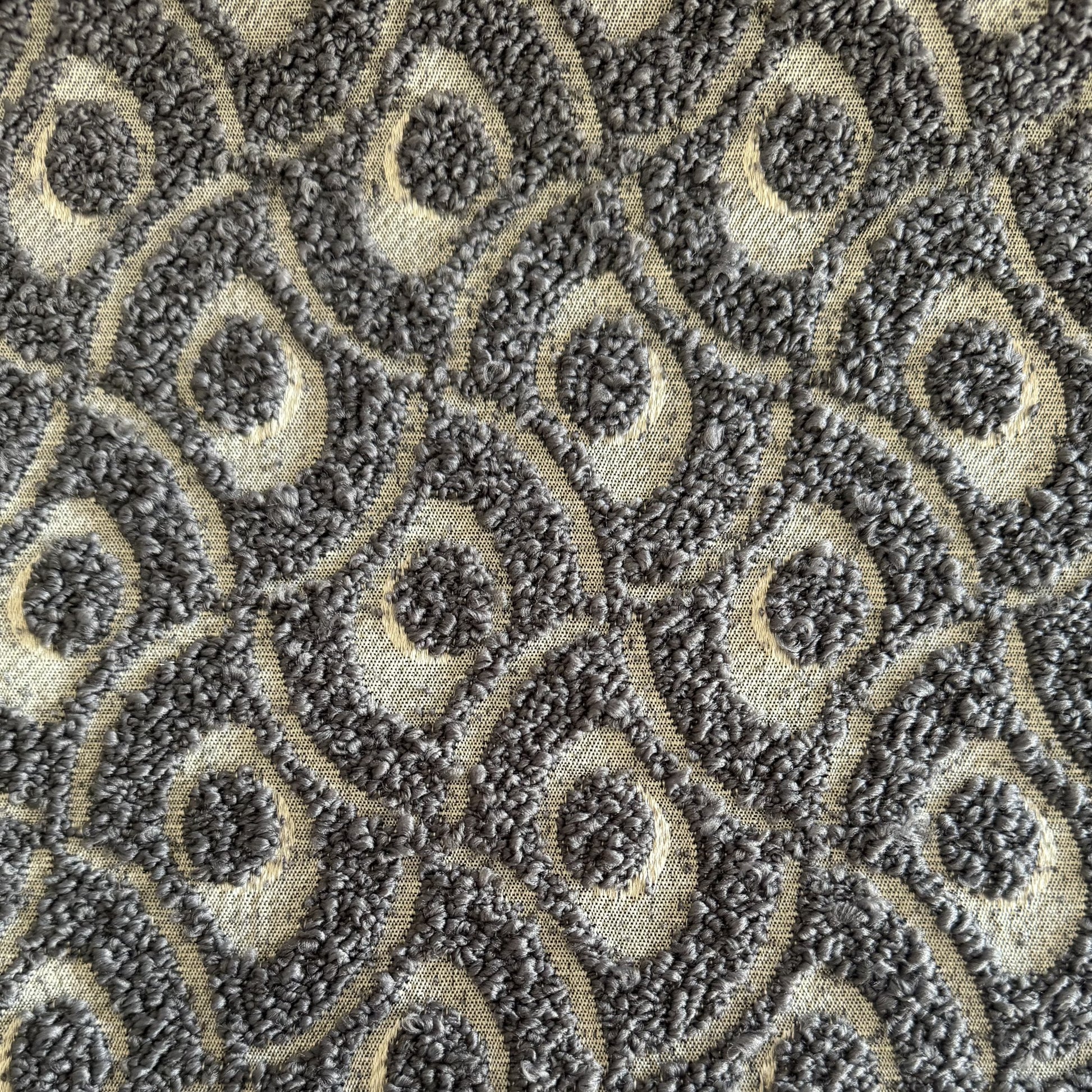 Gros plan sur un tissu bouclette gris  à motif géométrique en relief, tissé au Maroc pour l'ameublement et la décoration intérieure.