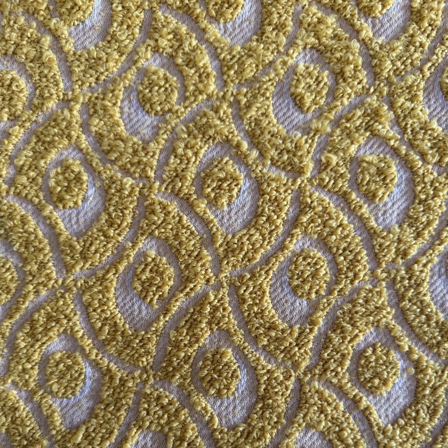 Gros plan sur un tissu bouclette jaune à motif géométrique en relief, tissé au Maroc pour l'ameublement et la décoration intérieure.