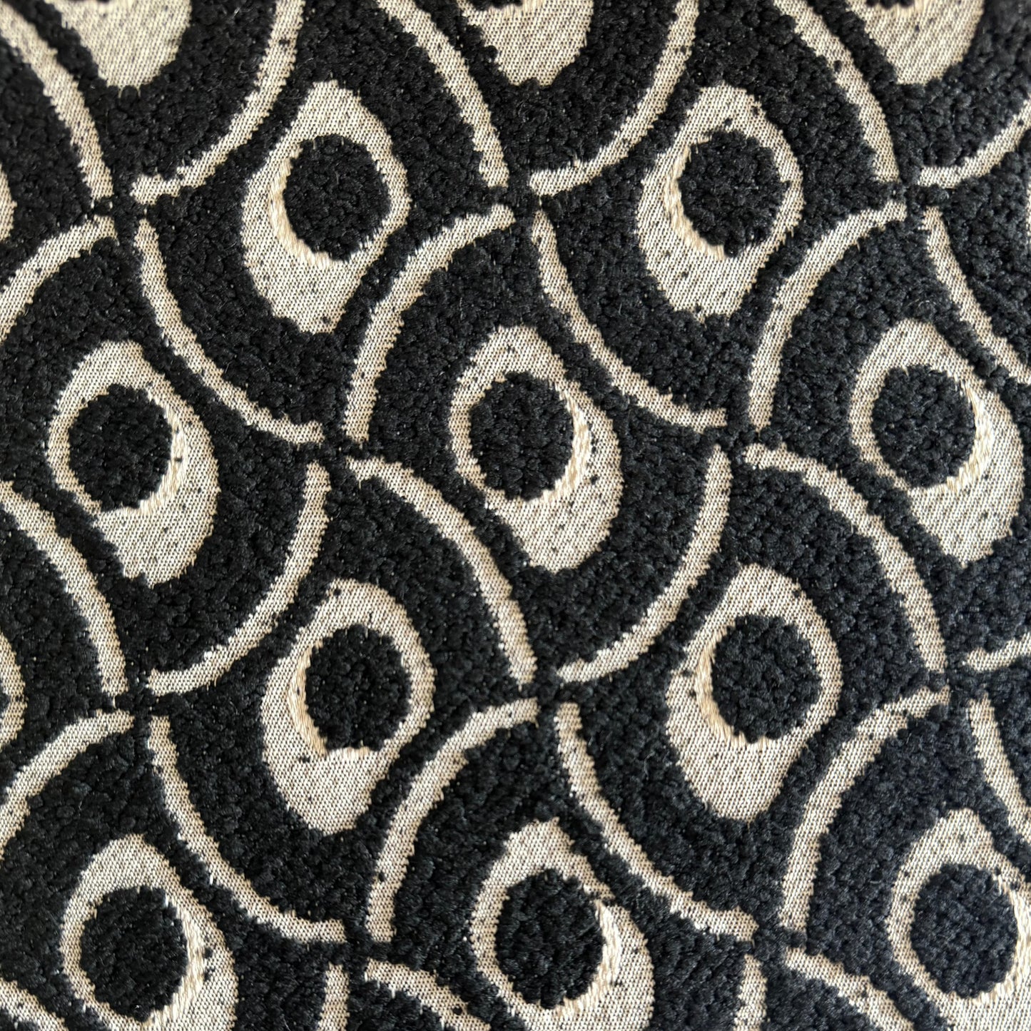 Gros plan sur un tissu bouclette noir à motif géométrique en relief, tissé au Maroc pour l'ameublement et la décoration intérieure.