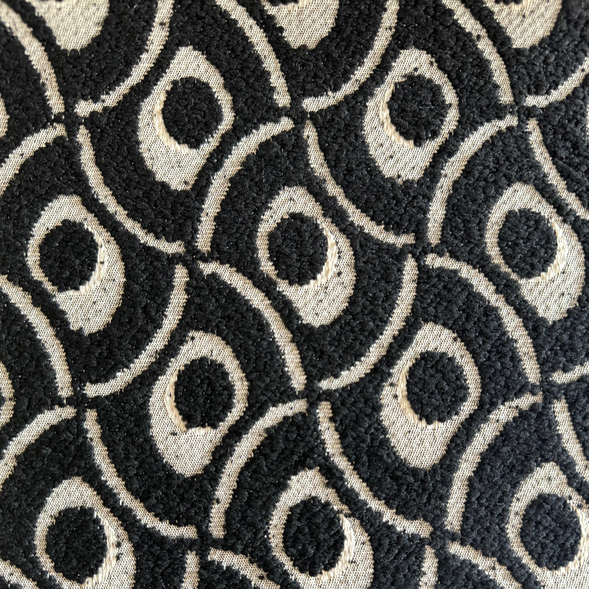 Gros plan sur un tissu bouclette noir à motif géométrique en relief, tissé au Maroc pour l'ameublement et la décoration intérieure.
