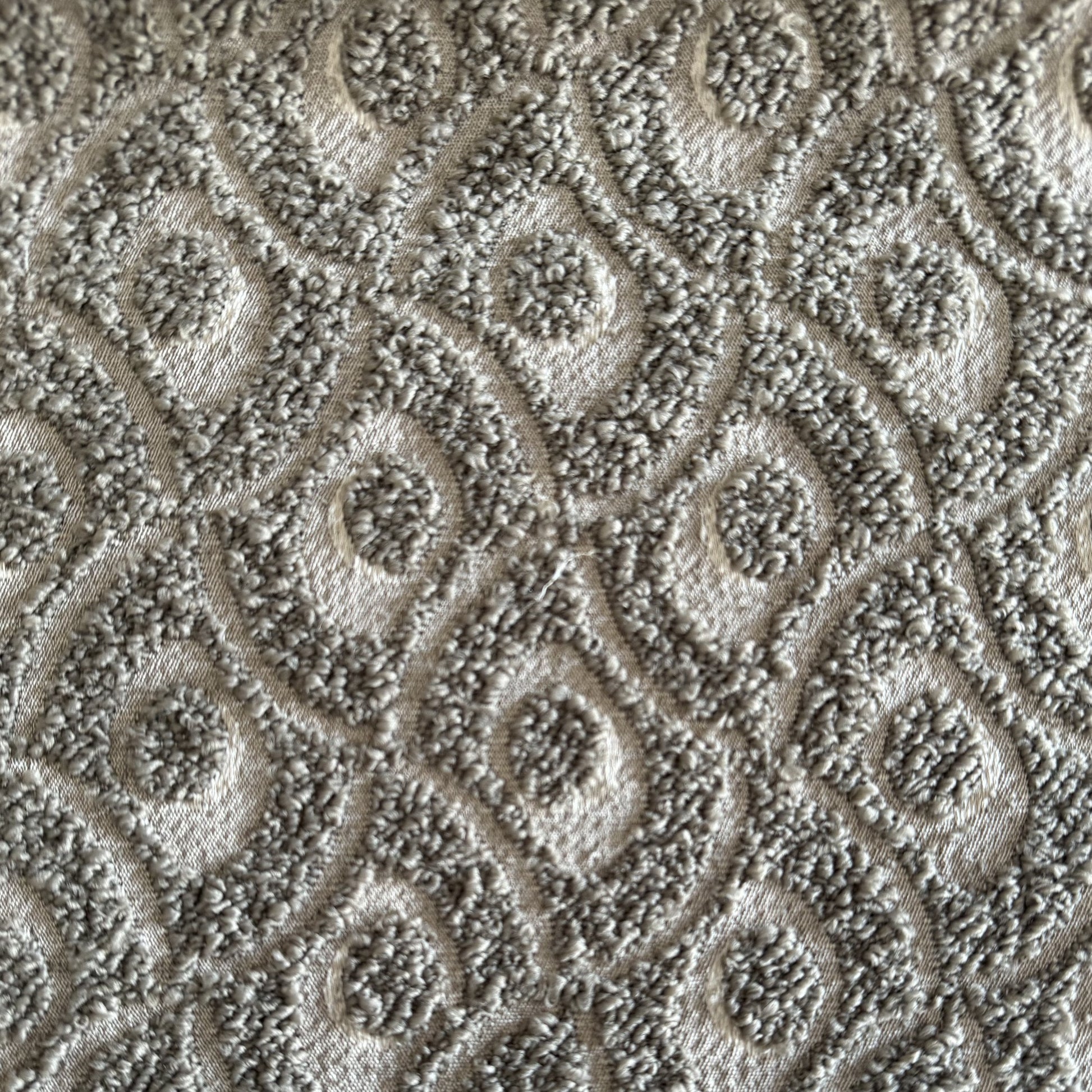 Gros plan sur un tissu bouclette taupe à motif géométrique en relief, tissé au Maroc pour l'ameublement et la décoration intérieure.
