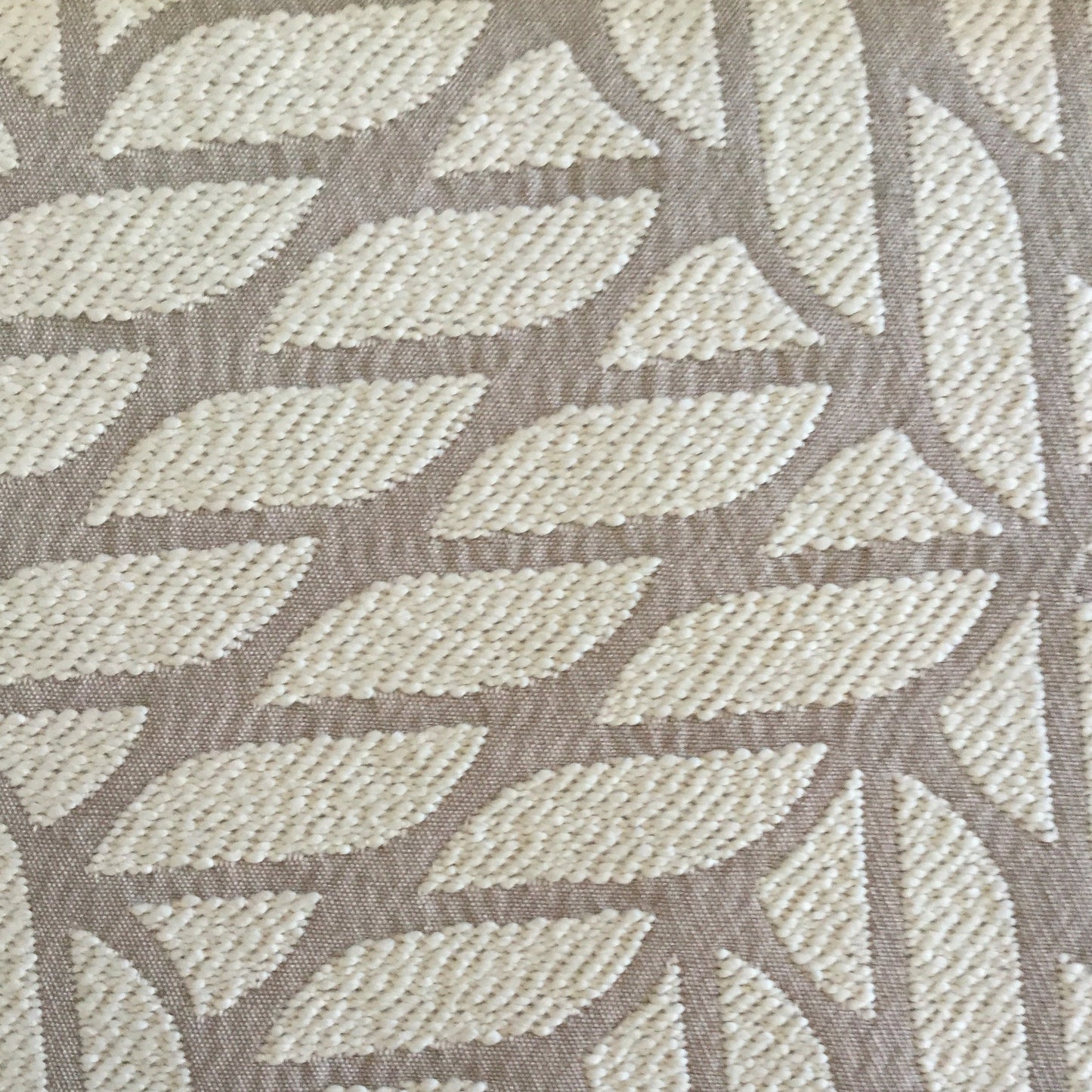 Gros plan d’un tissu d’ameublement en beige  à motif géométrique contemporain en relief, idéal pour la confection de coussins et décoration intérieure.
