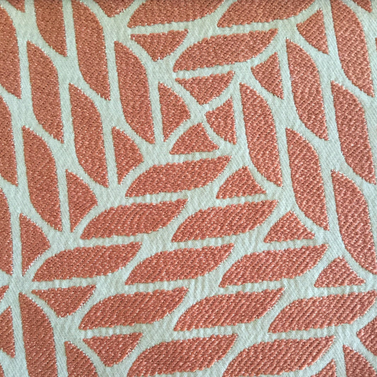 Gros plan d’un tissu d’ameublement en terracotta et écru à motif géométrique contemporain en relief, idéal pour la confection de coussins et décoration intérieure.

