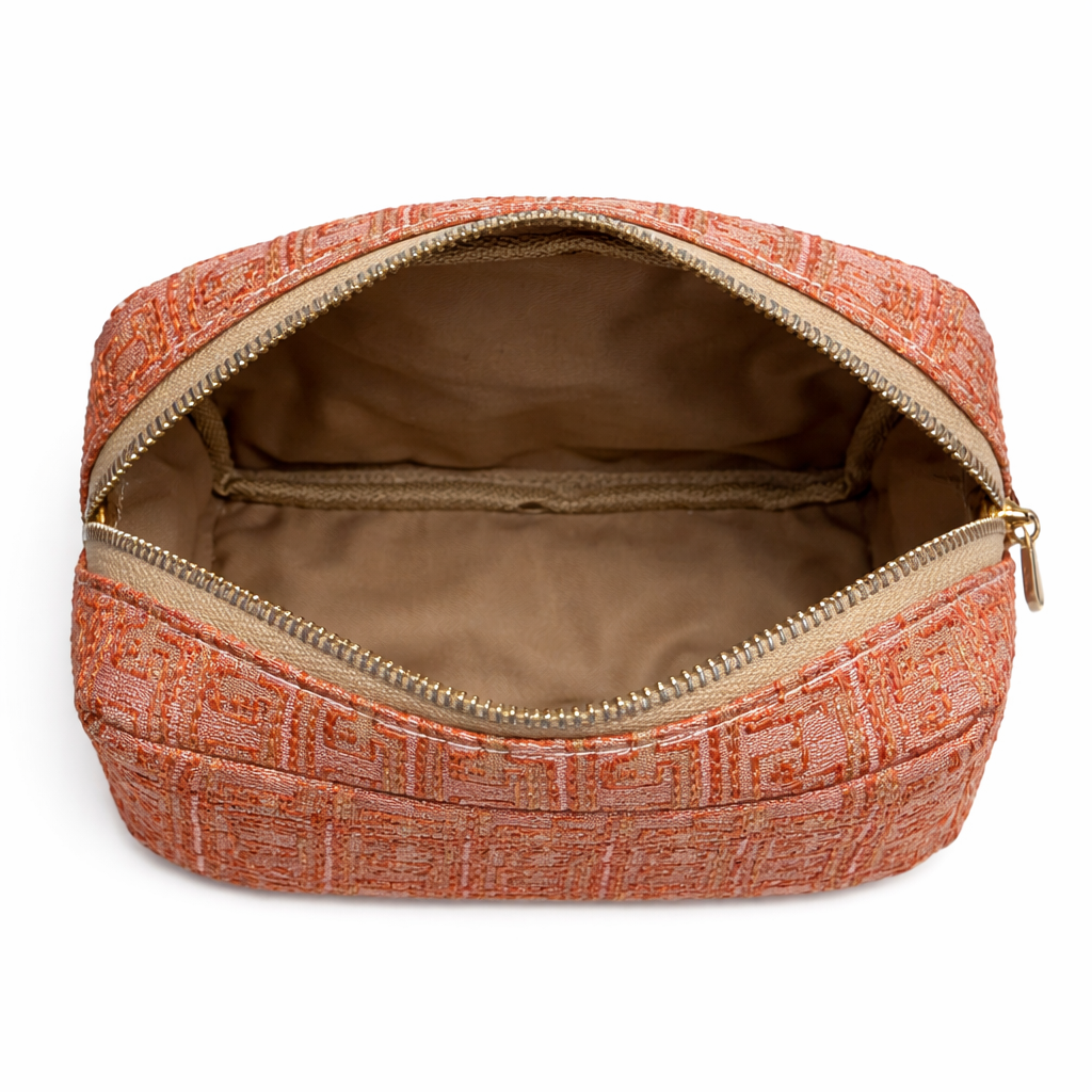 ntérieur d’une trousse de beauté corail à motif géométrique doré, avec compartiment principal spacieux et poche zippée intérieure pour organiser maquillage et accessoires, création Biyadi Collection.
