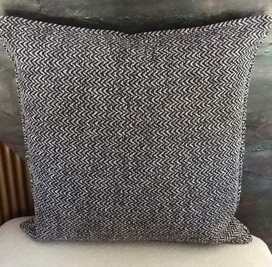 Coussin décoratif noir et écru à motif chevron tissé, texture en relief et finition soignée.