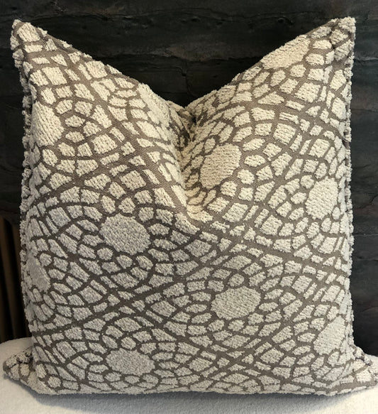Coussin décoratif en tissu texturé à relief, motif organique écru sur fond taupe .