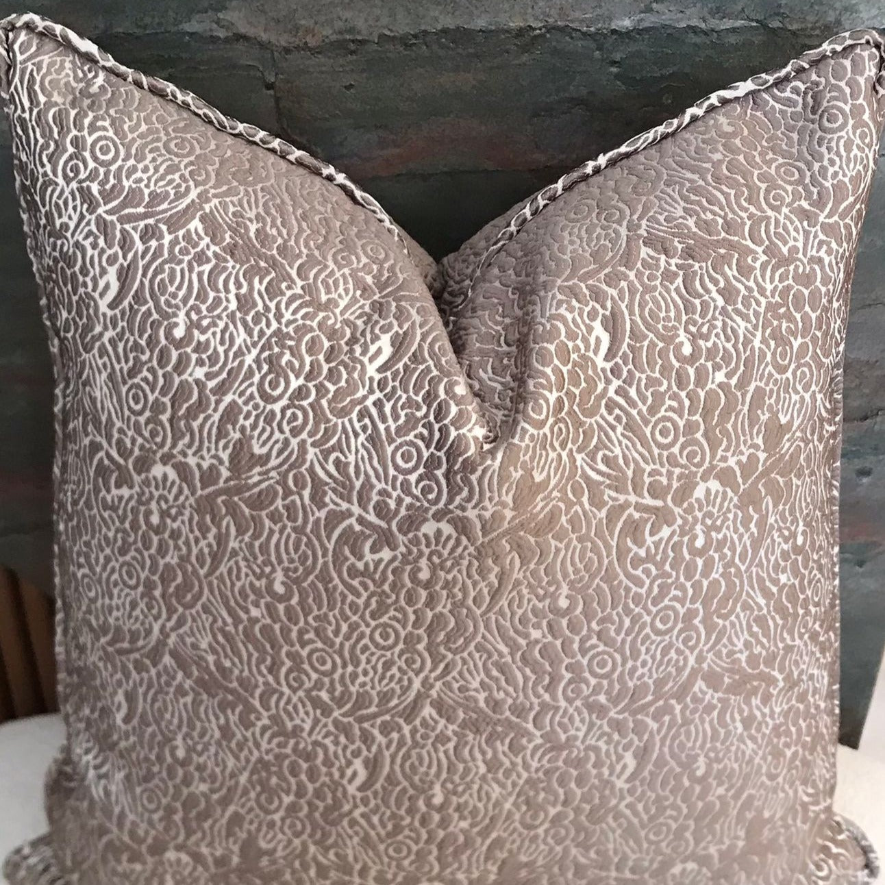 Coussin décoratif taupe à motif floral en relief avec effet texturé élégant, idéal pour une décoration intérieure chic et raffinée.