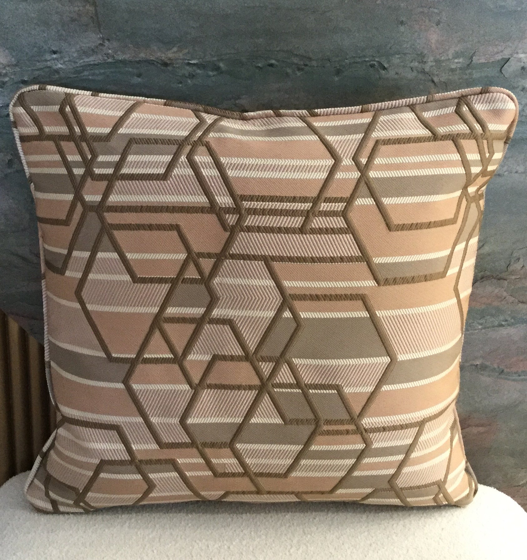 Coussin décoratif géométrique taupe et rose poudré avec motifs hexagonaux modernes tissés en relief.