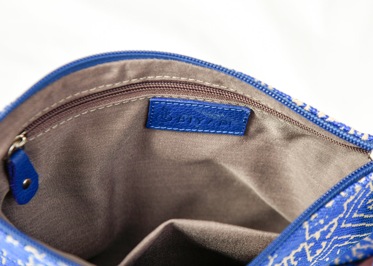 Intérieur d’une pochette bleue à motif marocain tissé avec doublure beige, poche zippée intérieure et finitions soignées Biyadi Collection.