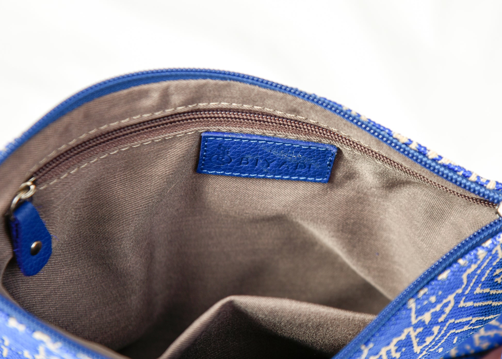 Intérieur d’une pochette bleue à motif marocain tissé avec doublure beige, poche zippée intérieure et finitions soignées Biyadi Collection.