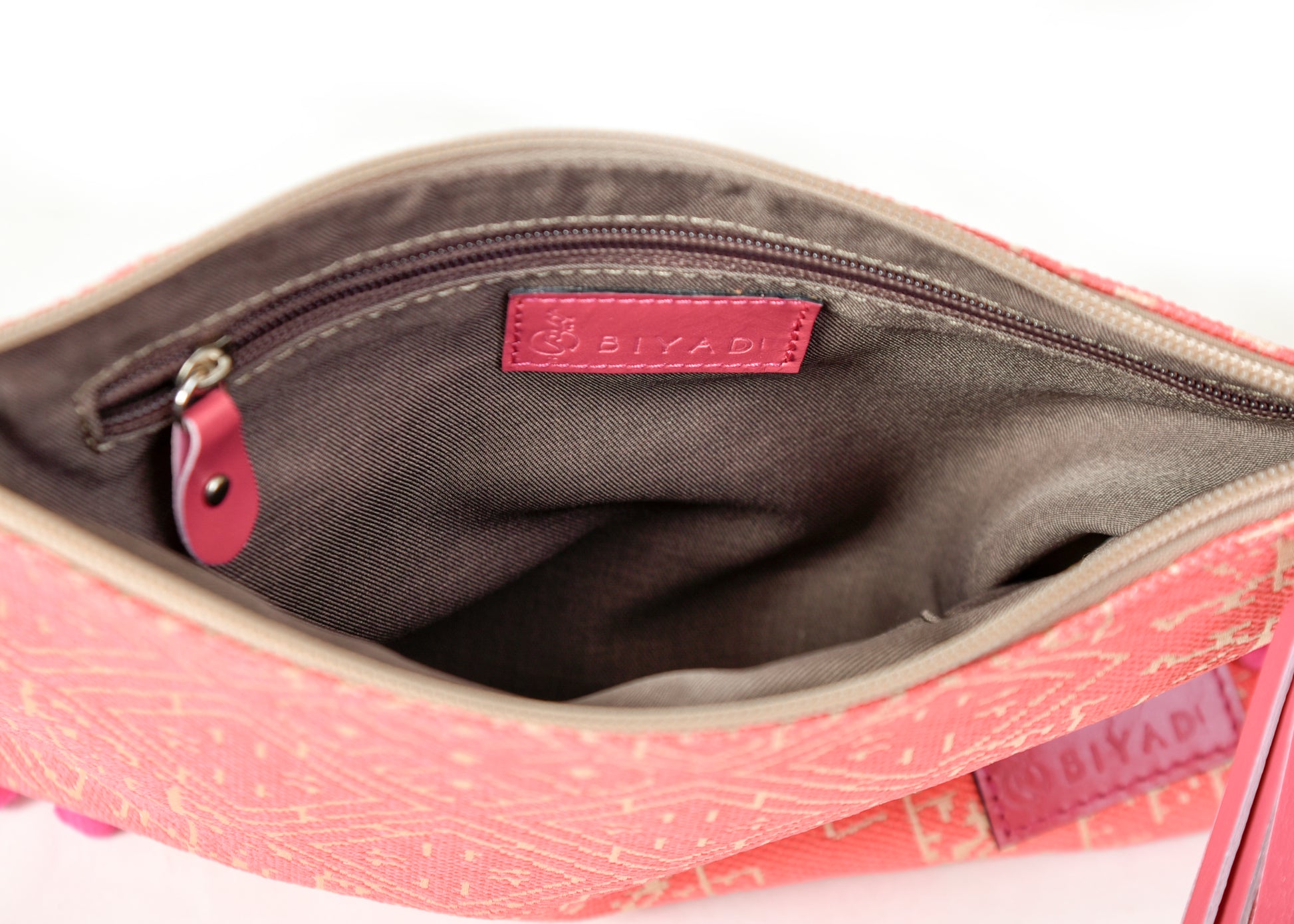 Intérieur d’une pochette corail à motif marocain tissé avec doublure beige, poche zippée intérieure et finitions soignées Biyadi Collection.