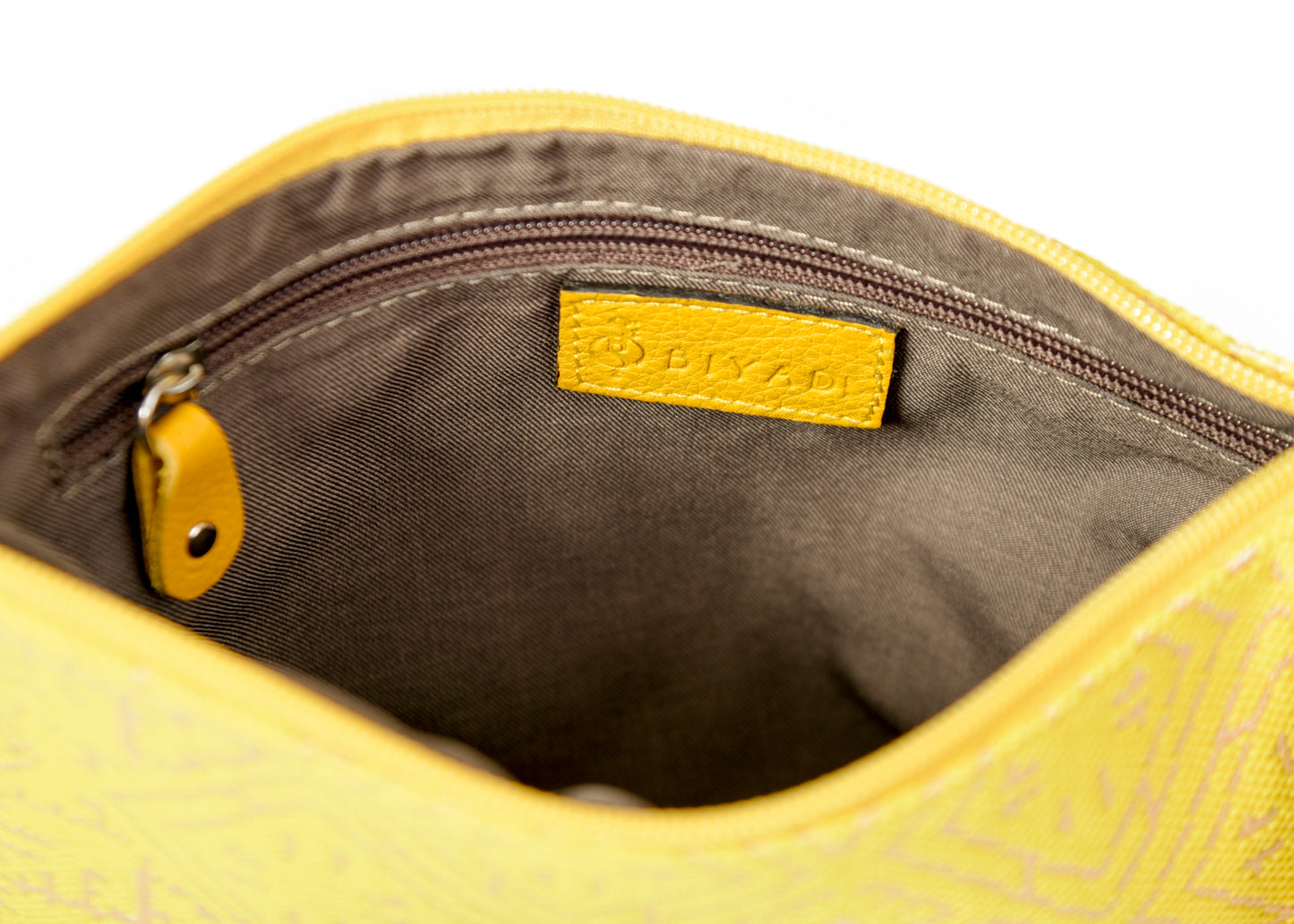 Intérieur d’une pochette jaune fluo à motif marocain tissé avec doublure beige, poche zippée intérieure et finitions soignées Biyadi Collection.