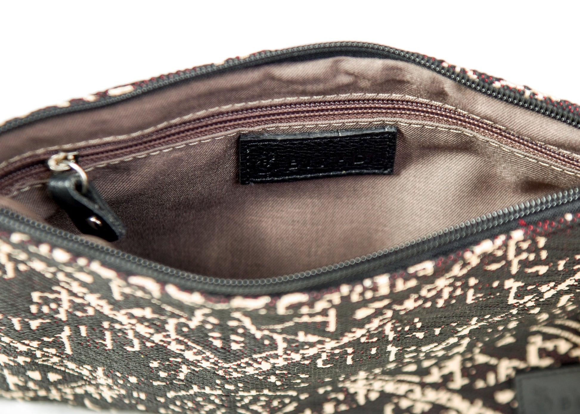 Intérieur d’une pochette noire à motif marocain tissé avec doublure beige, poche zippée intérieure et finitions soignées Biyadi Collection.
