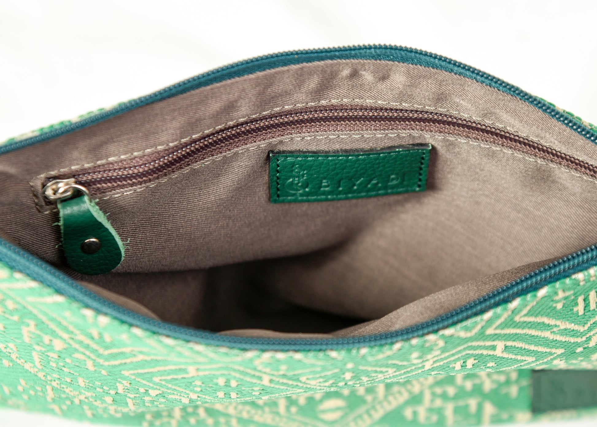 Intérieur d’une pochette vert à motif marocain tissé avec doublure beige, poche zippée intérieure et finitions soignées Biyadi Collection.