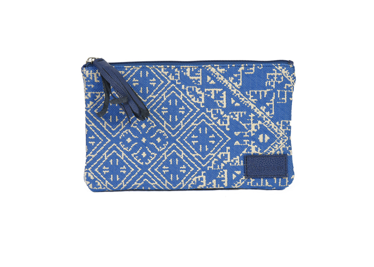 Petite pochette Tarz bleu en tissu tissé marocain à motifs géométriques écrus, avec fermeture zippée et pompon noir décoratif.