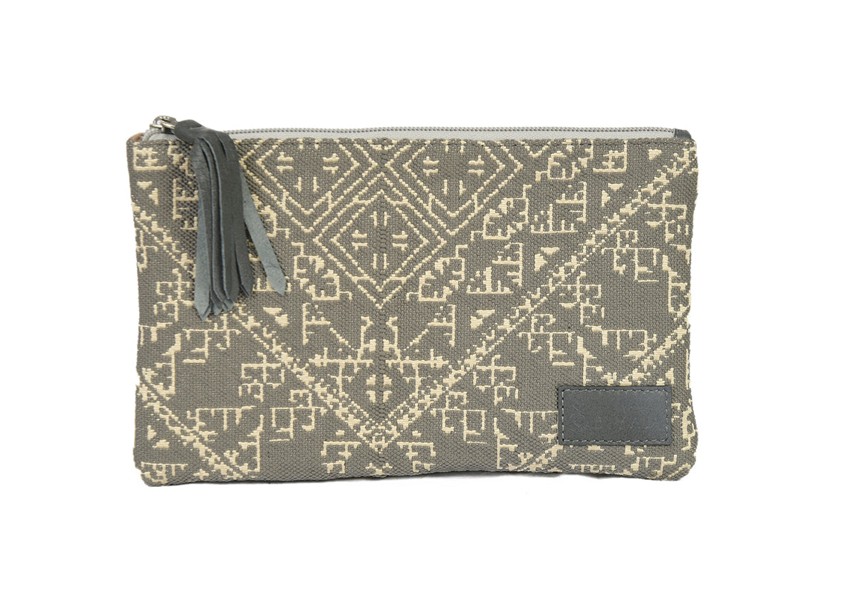 Petite pochette gris canard en tissu tissé marocain à motifs géométriques écrus, avec fermeture zippée et pompon noir décoratif.
