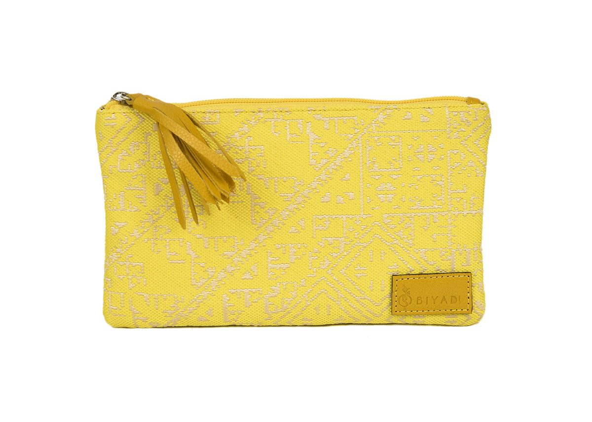 Petite pochette Tarz jaune canard en tissu tissé marocain à motifs géométriques écrus, avec fermeture zippée et pompon noir décoratif.