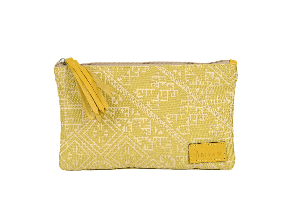 Petite pochette Tarz vert en tissu tissé marocain à motifs géométriques écrus, avec fermeture zippée et pompon noir décoratif.