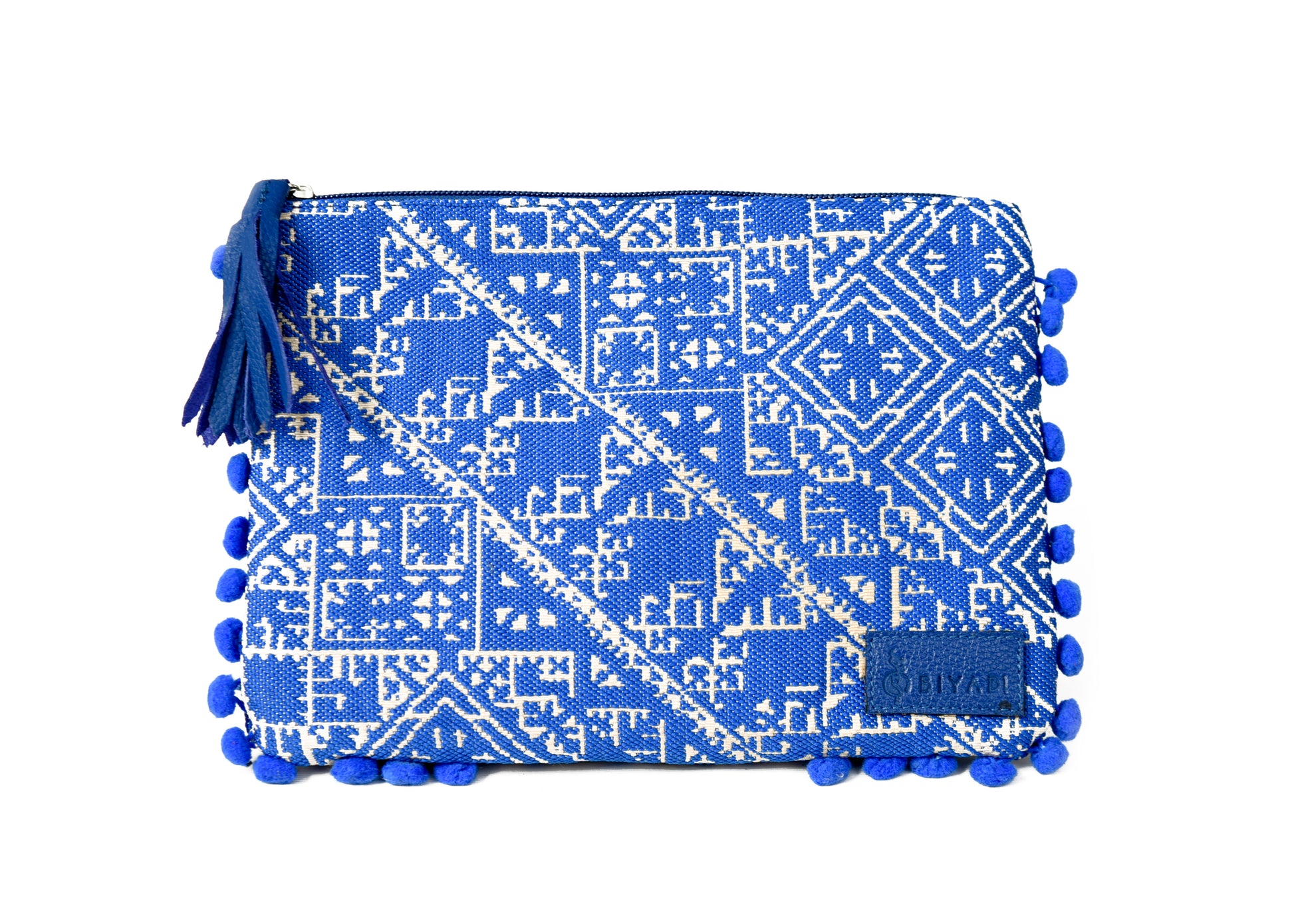 Pochette bleue cobalt à motif marocain tissé avec pompons décoratifs et fermeture zippée, idéale pour ranger maquillage, accessoires ou essentiels du quotidien, création Biyadi Collection.