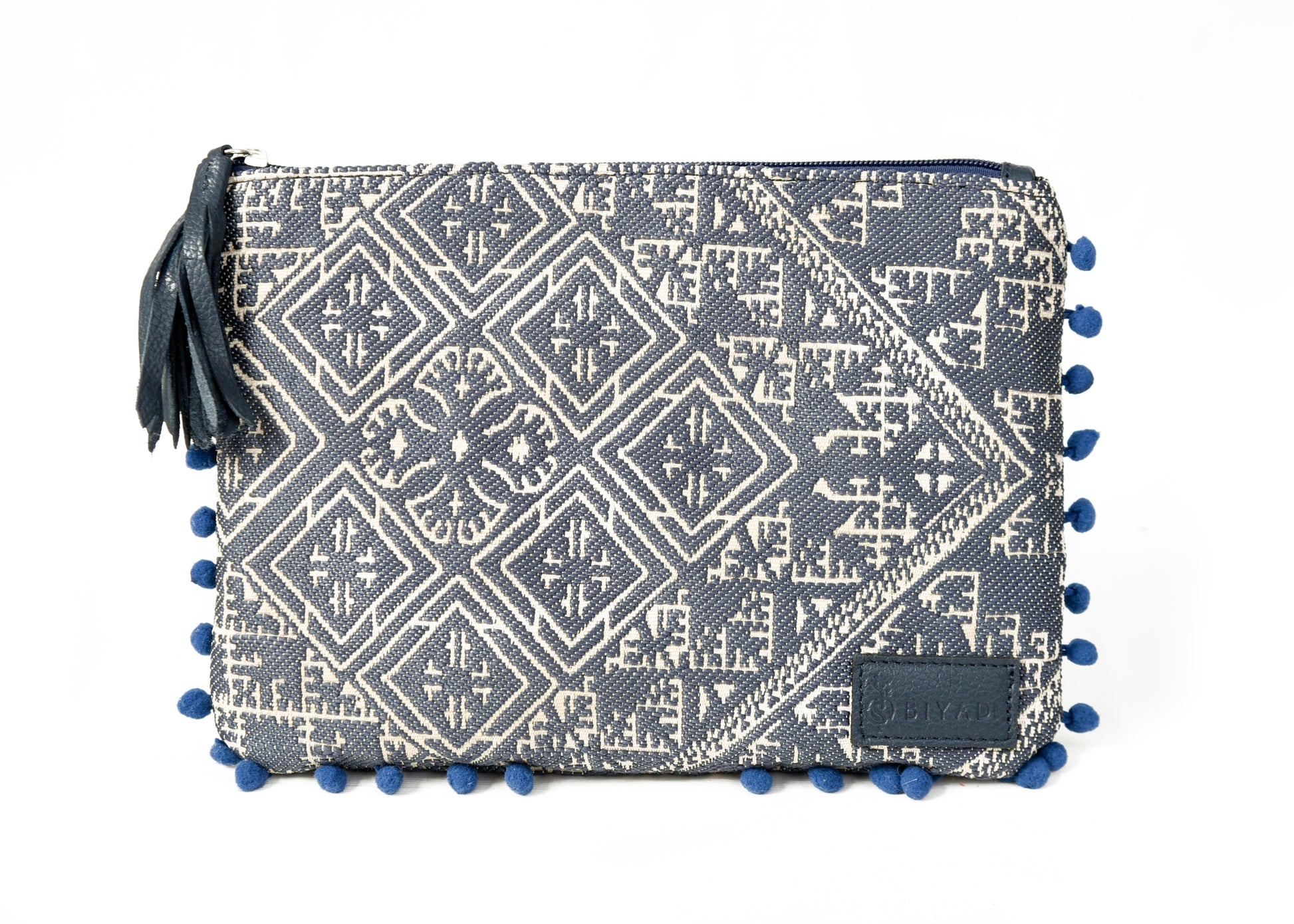 Pochette bleue marine à motif marocain tissé avec pompons décoratifs et fermeture zippée, idéale pour ranger maquillage, accessoires ou essentiels du quotidien, création Biyadi Collection.