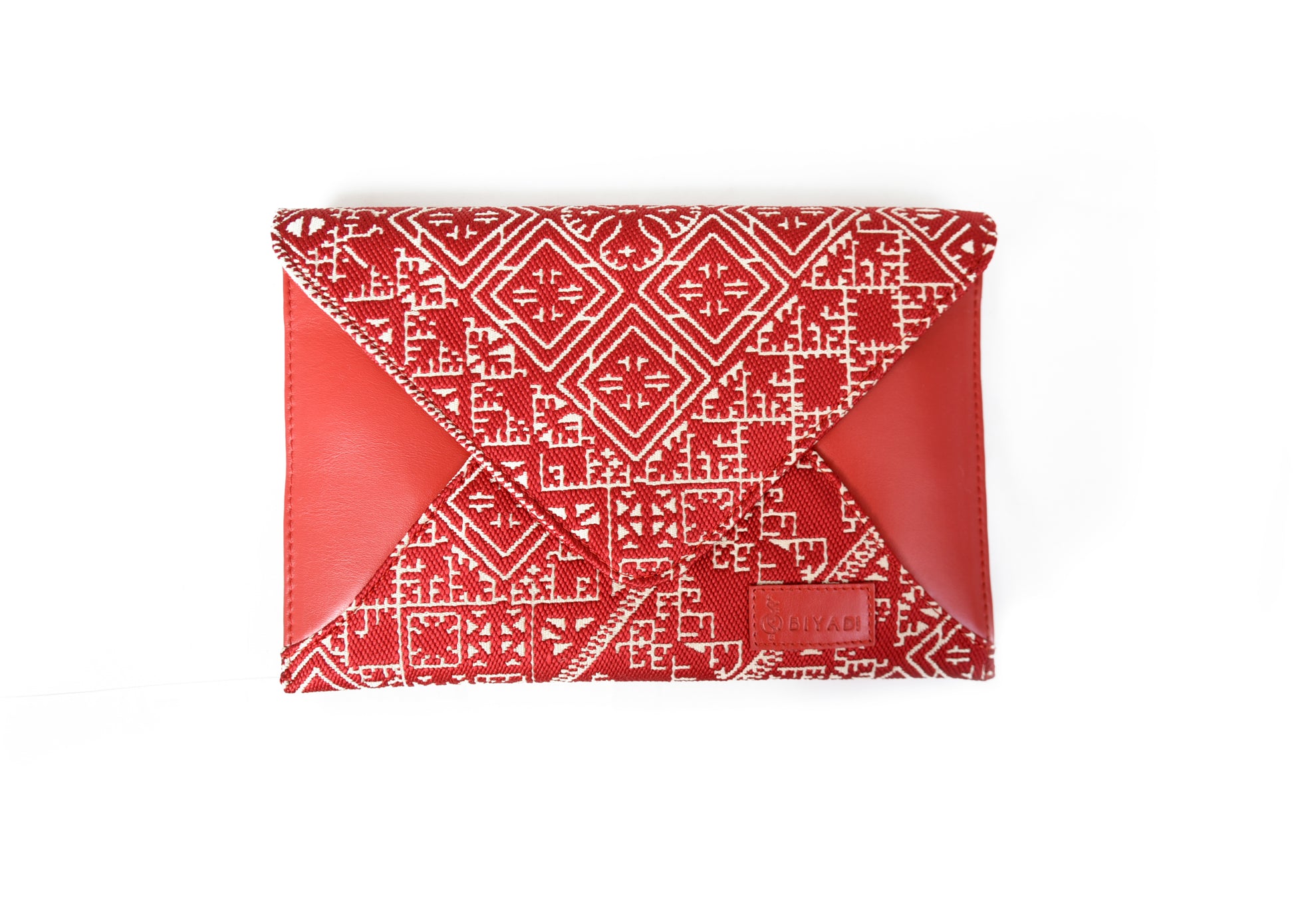 Pochette enveloppe rouge en tissu marocain tissé avec motif géométrique traditionnel et finitions en cuir, création Biyadi Collection.