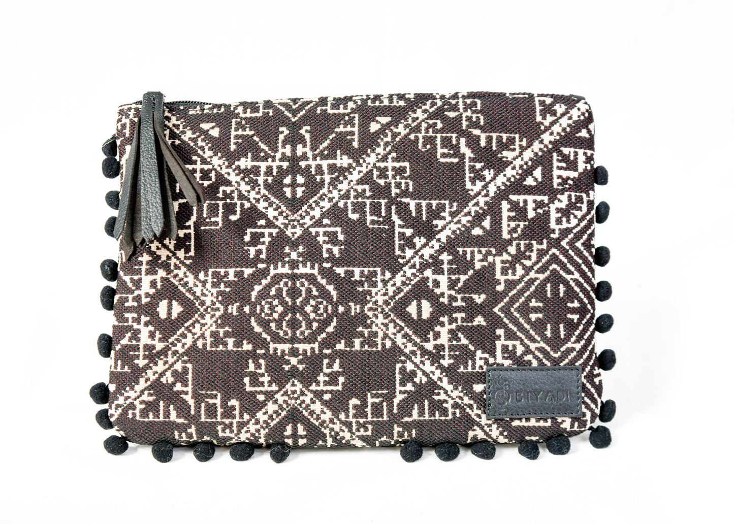 Pochette noire à motif marocain tissé avec pompons décoratifs et fermeture zippée, idéale pour ranger maquillage, accessoires ou essentiels du quotidien, création Biyadi Collection.