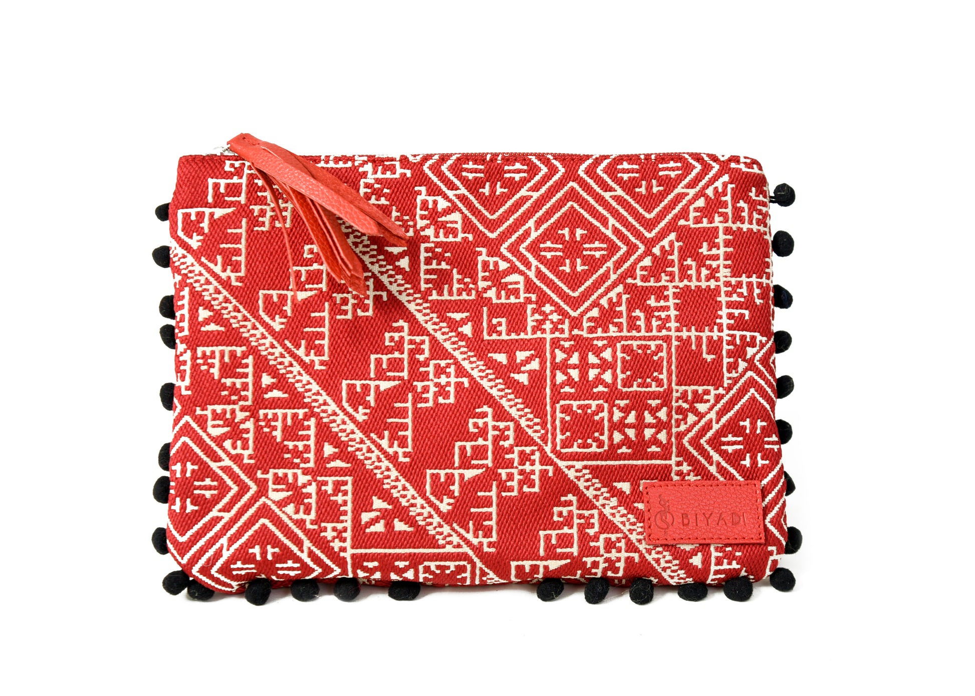 Pochette rouge à motif marocain tissé avec pompons décoratifs et fermeture zippée, idéale pour ranger maquillage, accessoires ou essentiels du quotidien, création Biyadi Collection.