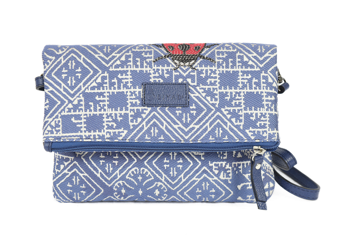 Sac bandoulière bleu  coccinelle en tissu marocain tissé, ornée d’un motif géométrique inspiré des broderies traditionnelles de Fès, avec fermeture zippée et finitions en cuir, création exclusive Biyadi Collection fabriquée au Maroc.