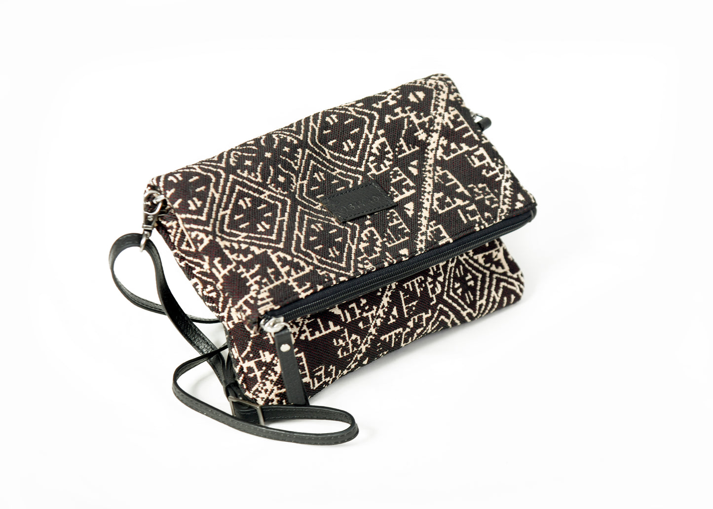 Sac bandoulière noir en tissu marocain tissé, ornée d’un motif géométrique inspiré des broderies traditionnelles de Fès, avec fermeture zippée et finitions en cuir, création exclusive Biyadi Collection fabriquée au Maroc.