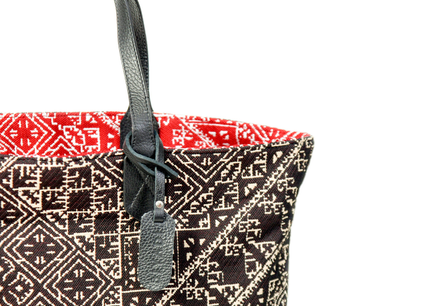 Détail du sac cabas reversible noir et rouge en tissu marocain tissé avec anse en cuir noir et étiquette en cuir Biyadi Collection.