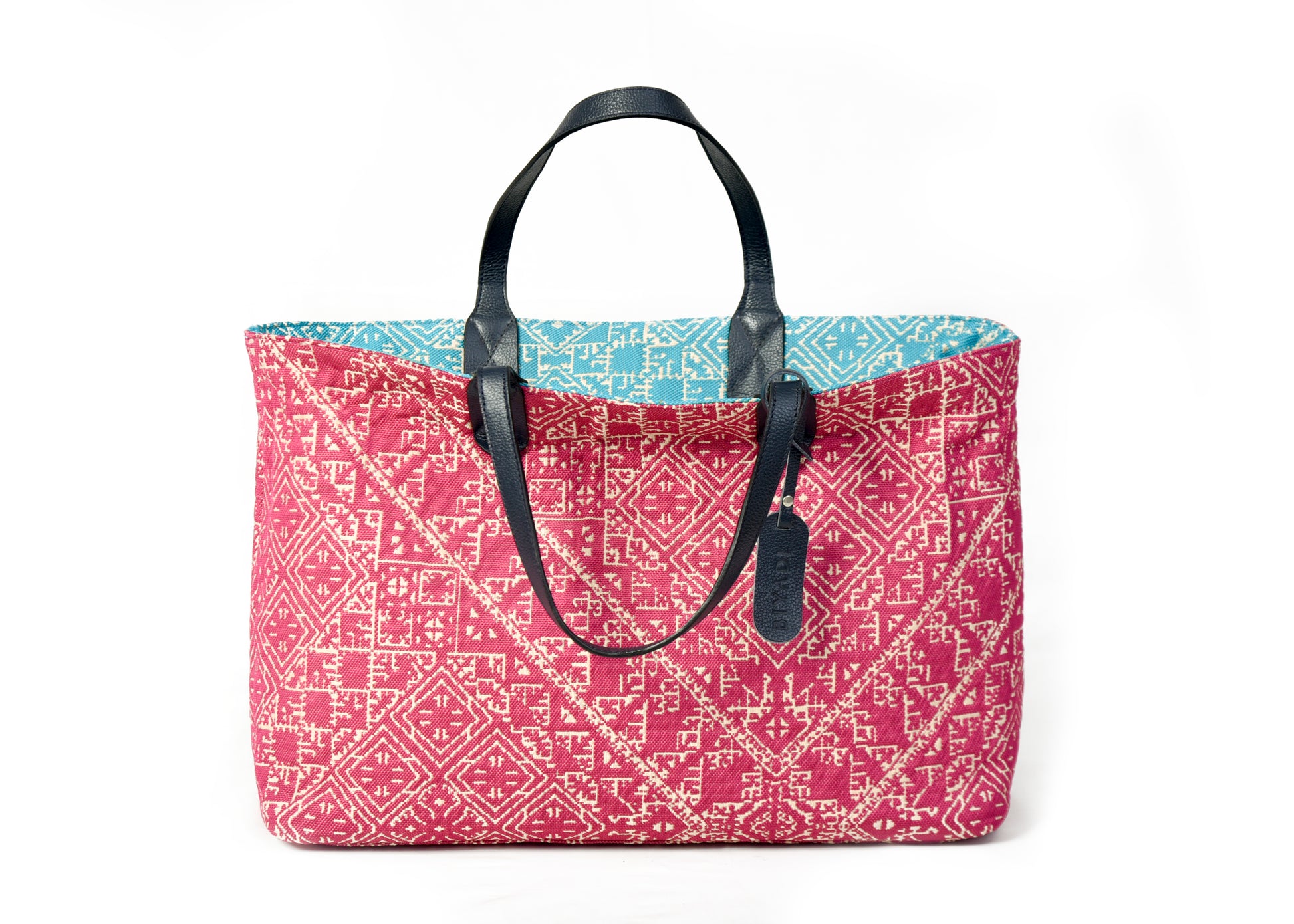Sac cabas réversible fushia et turquois  en tissu marocain tissé avec anses en cuir noir et motif géométrique inspiré du patrimoine marocain.