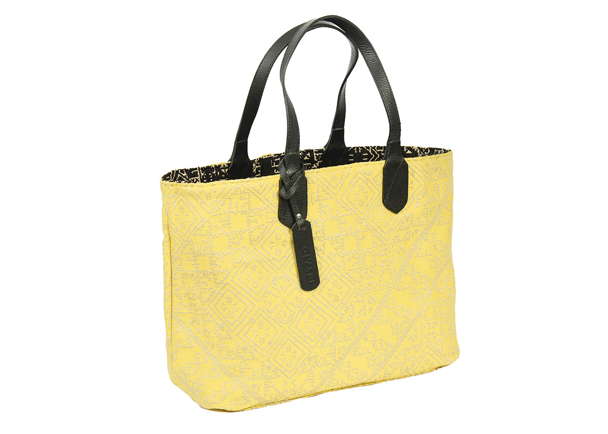 Sac cabas réversible jaune et noir en tissu marocain tissé avec anses en cuir noir et motif géométrique inspiré du patrimoine marocain.