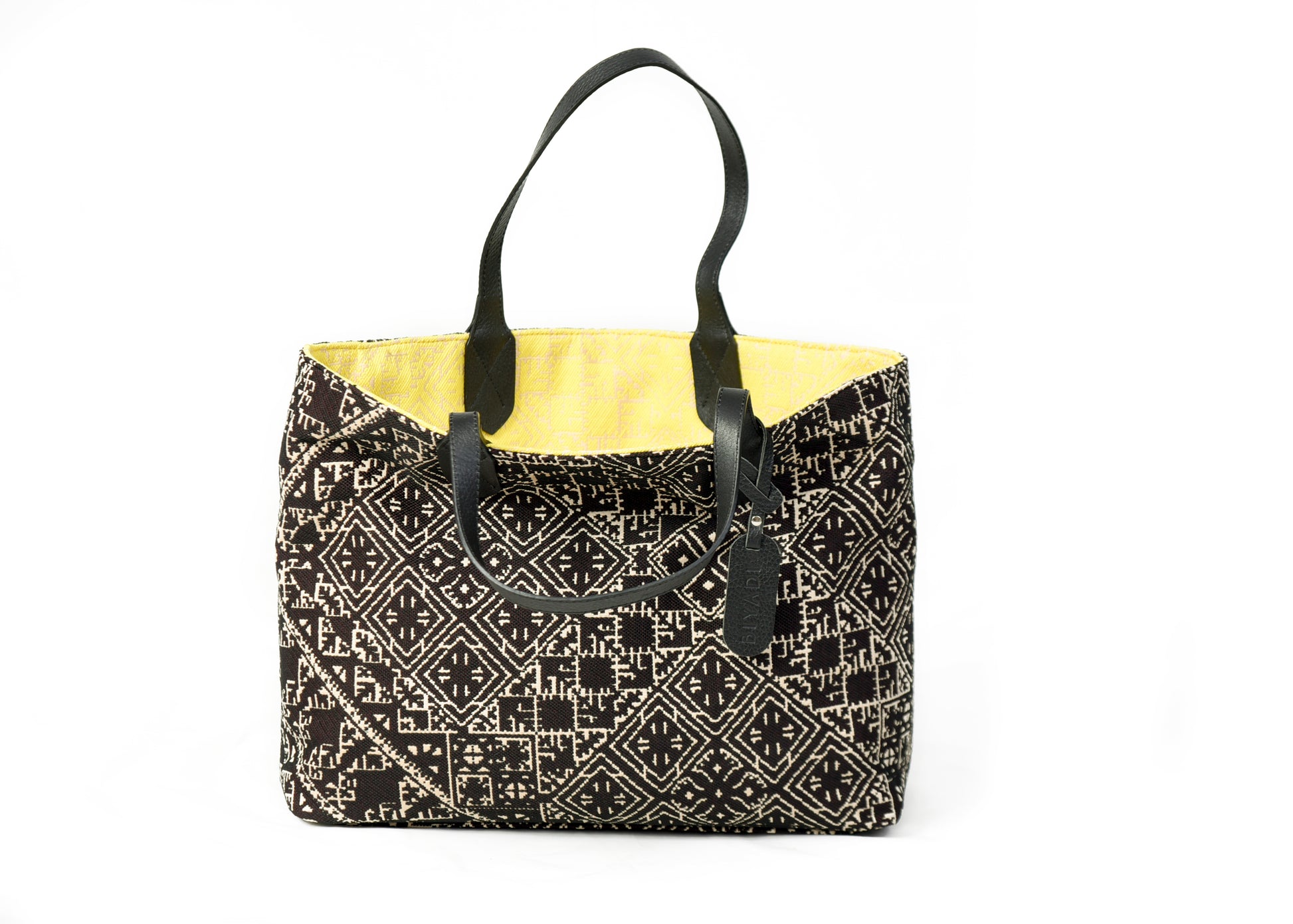 Sac cabas réversible jaune et noir en tissu marocain tissé avec anses en cuir noir et motif géométrique inspiré du patrimoine marocain.