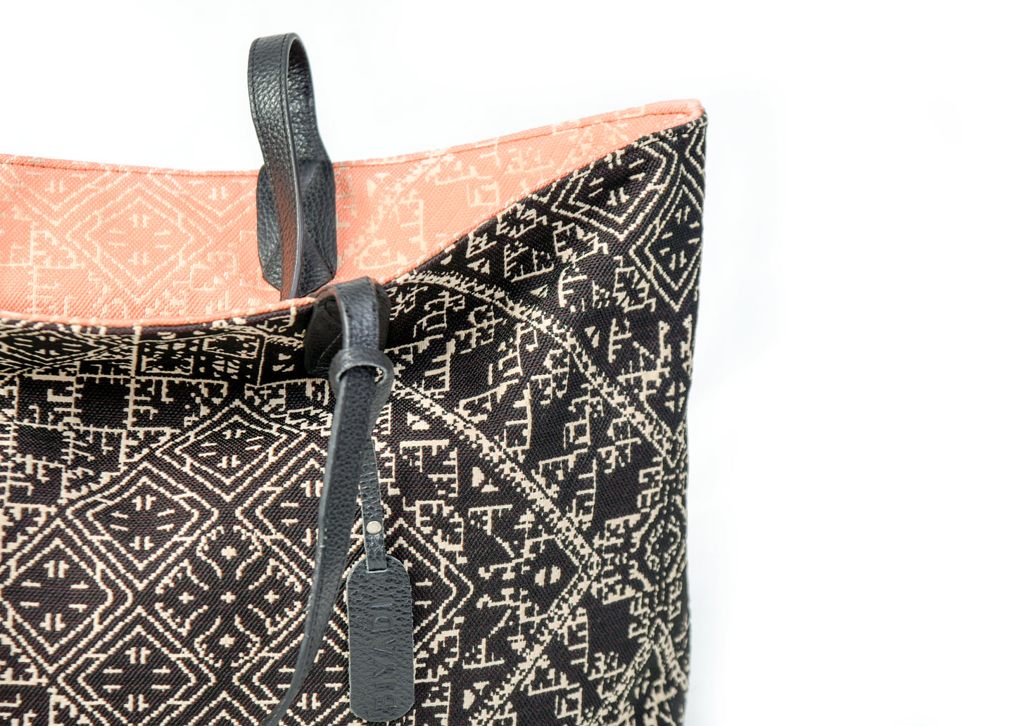 Détail du sac cabas reversible noir et corail en tissu marocain tissé avec anse en cuir noir et étiquette en cuir Biyadi Collection.